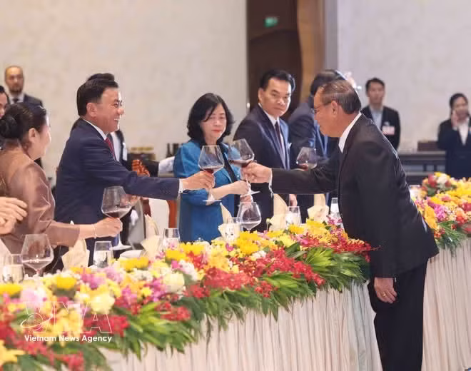 El miembro del Buró Político y permanente del Secretariado del Comité Central del Partido Popular Revolucionario de Laos, Vilay Lakhamphong (derecha), ofrece un banquete a su homólogo del Partido Comunista de Vietnam, Tran Cam Tu. (Foto: VNA)