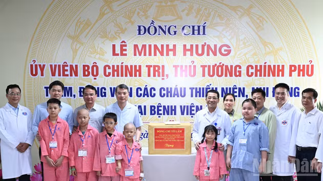 El primer ministro Le Minh Hung entrega los regalos enviados por el secretario general del Partido Comunista y presidente del Estado, To Lam, a los pacientes pediátricos que reciben tratamiento en el Hospital K, centro de Tan Trieu, barrio de Thanh Liet.