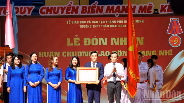 Tran Luu Quang, miembro del Buró Político y secretario del Comité del Partido en Ciudad Ho Chi Minh, entrega la Orden del Trabajo de segunda clase a la Escuela Secundaria Superior Tran Khai Nguyen.