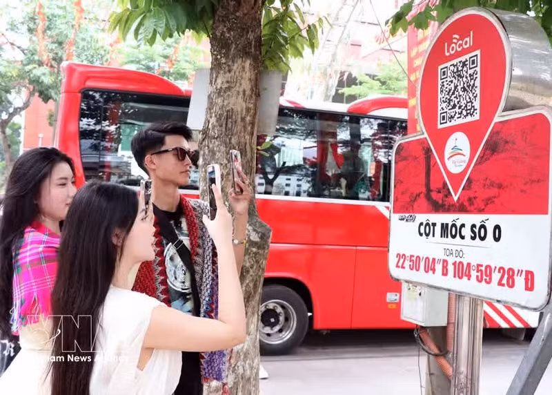 Los visitantes escanean un código QR en el marcador del kilómetro 0 de la provincia de Ha Giang para acceder a información turística. (Foto: VNA)