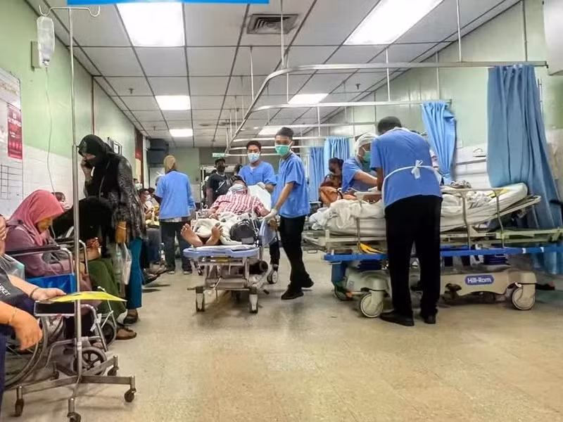 Un auxiliar médico (vestido con pantalones y zapatos negros) traslada a un paciente en una camilla por el pasillo, una zona pública, del departamento de urgencias y traumatología del Hospital Raja Permaisuri Bainun, en Ipoh, Perak (Foto: codeblue.galencentre.org)