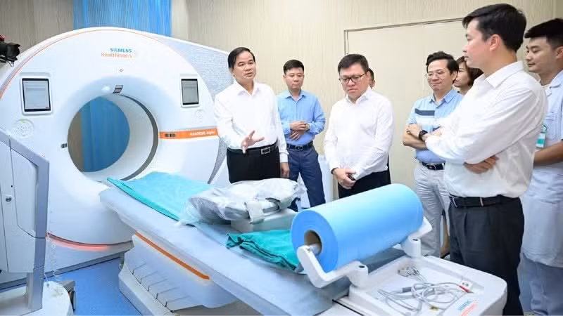 Le Quoc Minh y delegados del periódico Nhan Dan visitan modernos equipos médicos del hospital Bach Mai.