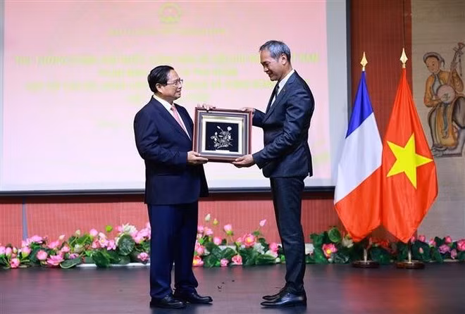 El primer ministro Pham Minh Chinh entrega obsequios a representantes de la comunidad vietnamita en Francia. (Foto: VNA)