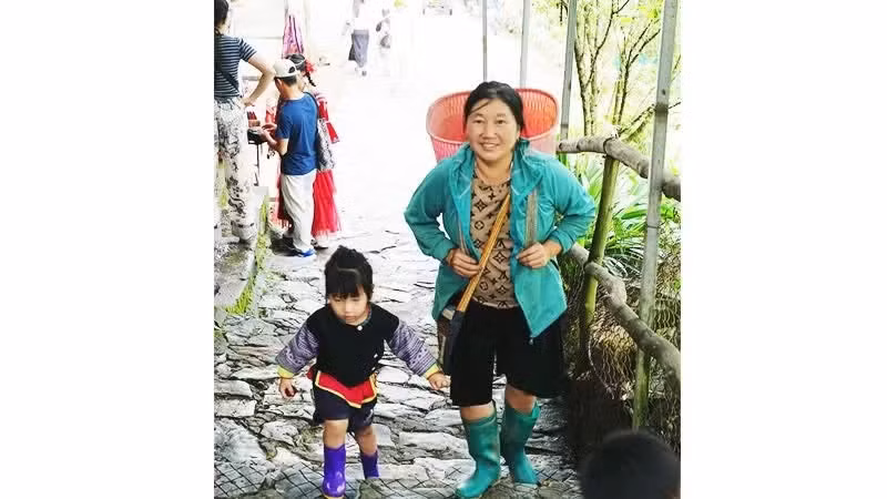 Una madre lleva a su hijo mientras trabaja.