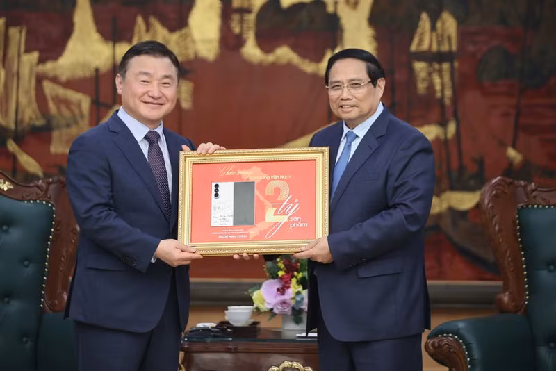 El primer ministro Pham Minh Chinh (derecha) entrega una placa conmemorativa de la producción del teléfono móvil número dos mil millones de Samsung en Vietnam a Roh Tae Moon (Foto: baochinhphu.vn)