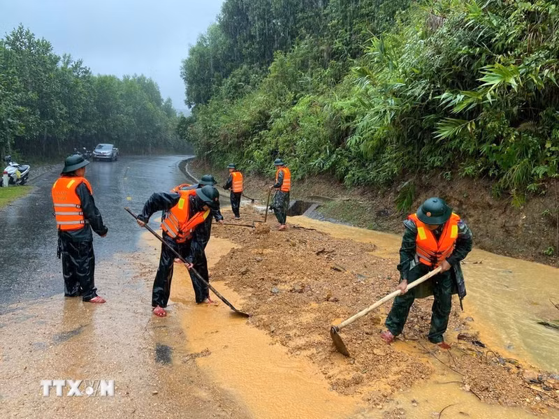 Guardias fronterizos de la ciudad de Hue excavan tierra y rocas para nivelar la carretera afectada por el deslizamiento de tierra en el paso de Pe Ke, en la comuna de A Luoi 1. (Foto: VNA)
