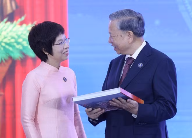 La directora general de VNA, Vu Viet Trang, entrega al secretario general To Lam el libro de fotografías "La gloria pertenece por siempre al pueblo". (Foto: VNA)