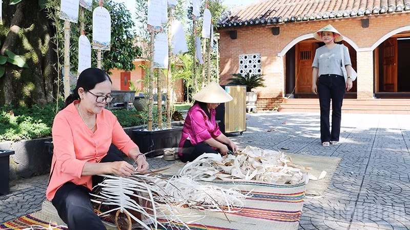 Los visitantes conocen las técnicas artesanales para elaborar productos a partir de hojas de palma de areca en la antigua aldea de Loc Yen. (Foto: Anh Quan)