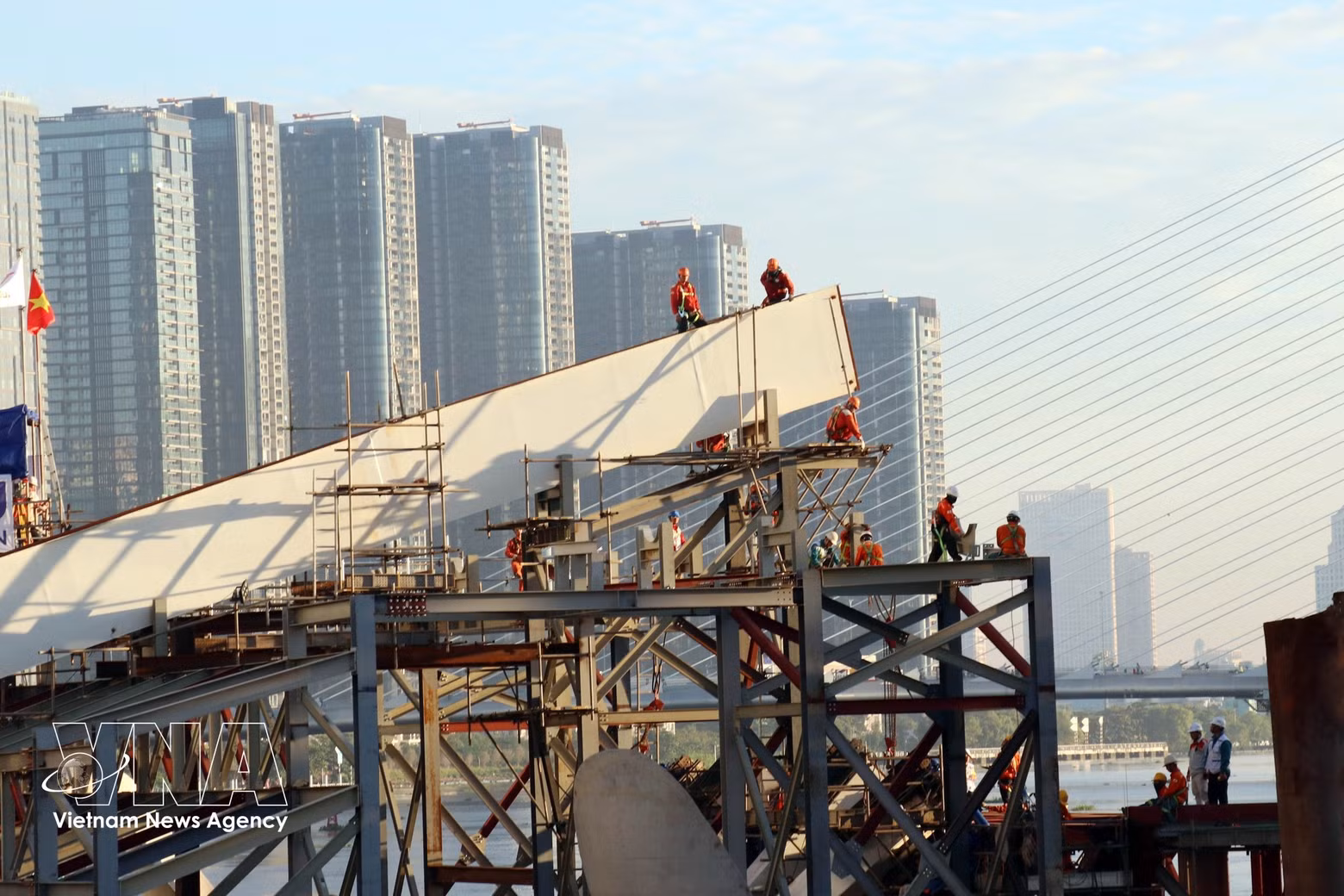 Ingenieros y trabajadores en la obra, durante los preparativos para el cierre del vano principal del puente peatonal sobre el río Saigón. (Foto: VNA)