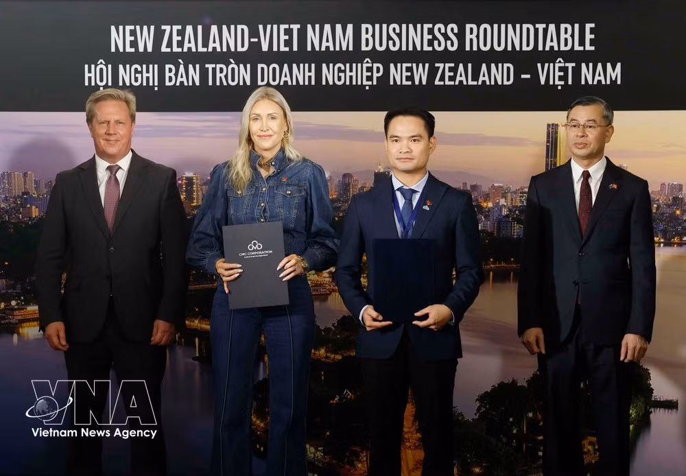 En presencia del ministro de Finanzas de Vietnam, Ngo Van Tuan (primero a la derecha), y del ministro neozelandés de Comercio e Inversiones, Todd McClay, representantes de empresas y organizaciones de ambos países intercambian documentos de cooperación durante la mesa redonda. (Foto: VNA)
