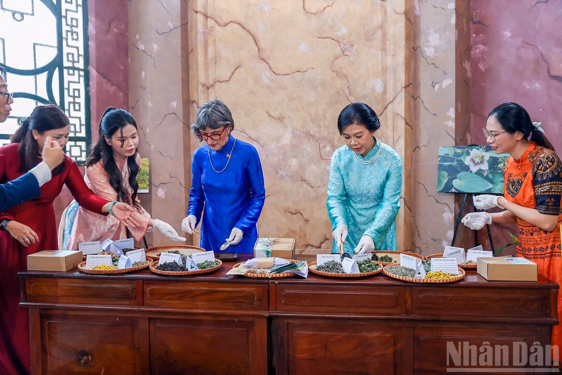 Ngo Phuong Ly, esposa del secretario general del Partido Comunista y presidente de Vietnam, To Lam, y Caroline Parmelin, cónyuge del presidente suizo, Guy Parmelin, participan en la elaboración de almohadillas térmicas tradicionales con hierbas medicinales.