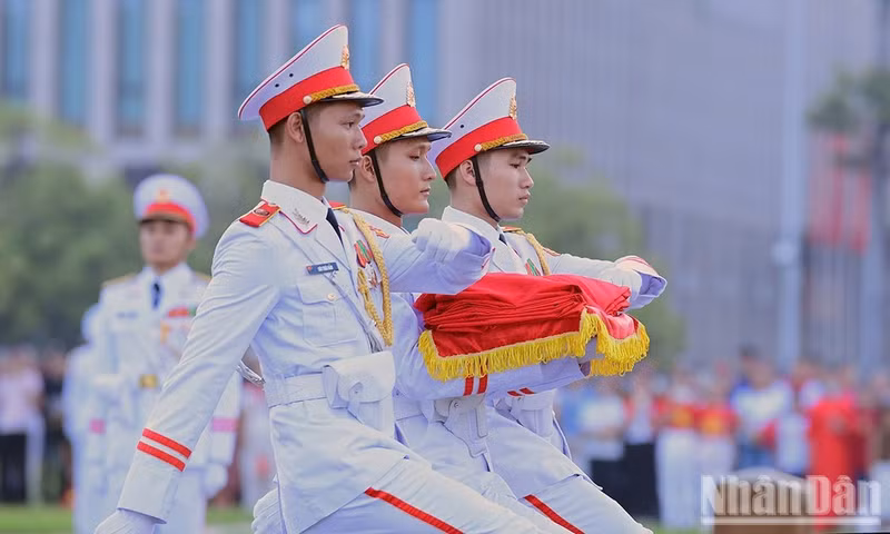 Tres soldados que portan la bandera nacional, avanzan hacia el asta. (Foto: Tung Mai)