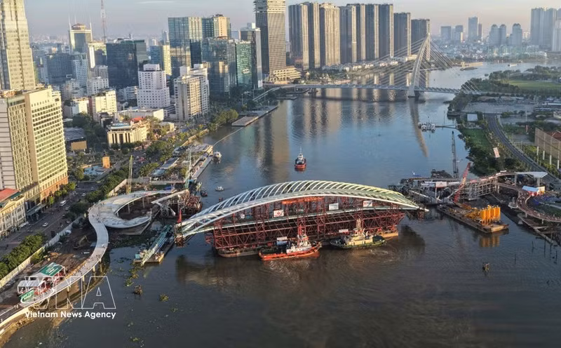 Vista panorámica de la barcaza que transporta el vano principal del puente peatonal sobre el río Saigón, situada en posición para su unión con la estructura. (Foto: VNA)