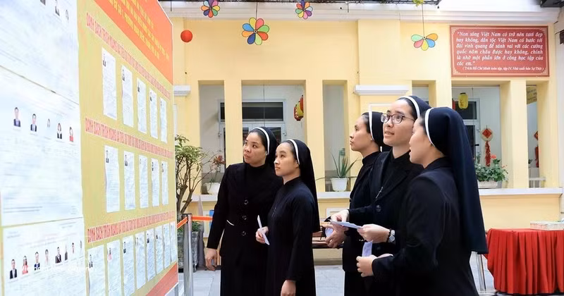 Monjes de la Congregación de las Hermanas de la Caridad de la Santa Cruz consultan la lista de candidatos en el colegio electoral No. 1, barrio de Hoan Kiem, Hanói. (Foto: VNA)