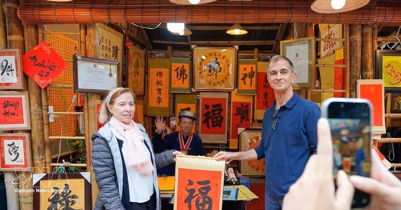 Los turistas internacionales disfrutan de la tradición de recibir caligrafía auspiciosa a principios de año. (Foto: VNA)