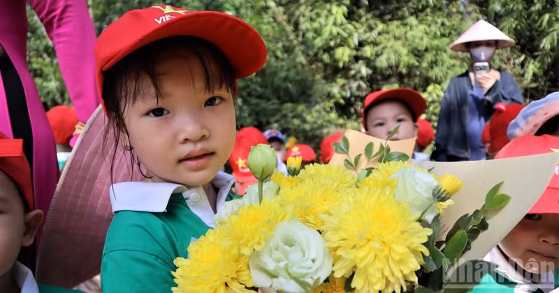 Los niños llevan hermosos ramos de flores para ofrecer al querido Tío Ho.