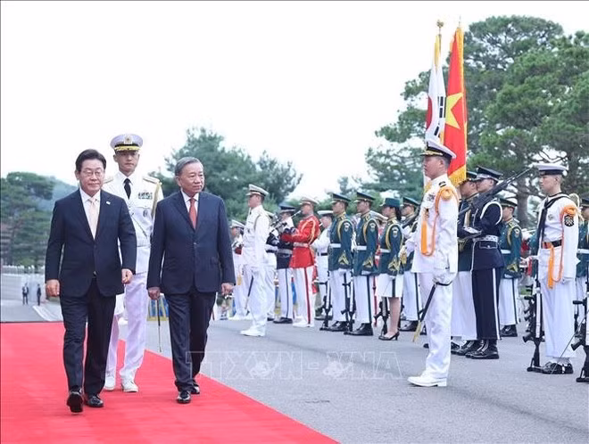 El presidente Lee Jae Myung y el secretario general To Lam (derecha) pasan revista a la guardia de honor en la ceremonia de bienvenida. Foto: VNA