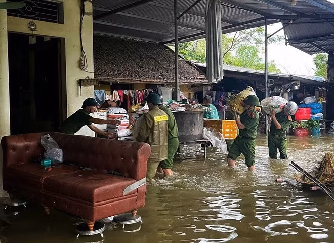 La policía y las fuerzas de seguridad ayudan a los pobladores en una zona inundada trasladar sus pertenencias. (Foto: VNA)
