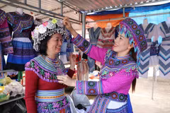 Turistas experimentan el uso de trajes tradicionales de la etnia H’Mong en el mercado de Dak R’mang. (Foto: VNA)