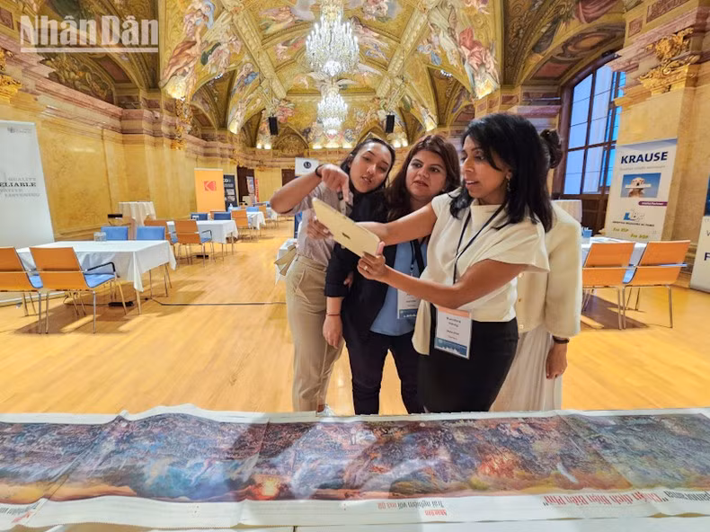 Asistentes a la Cumbre aprecian el producto del periódico Nhan Dan.
