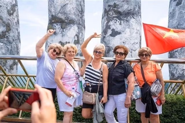 Los turistas extranjeros posan para una foto en el mundialmente famoso Puente Dorado dentro del complejo Sun World de Ba Na Hills en la ciudad de Da Nang (Foto: VNA)
