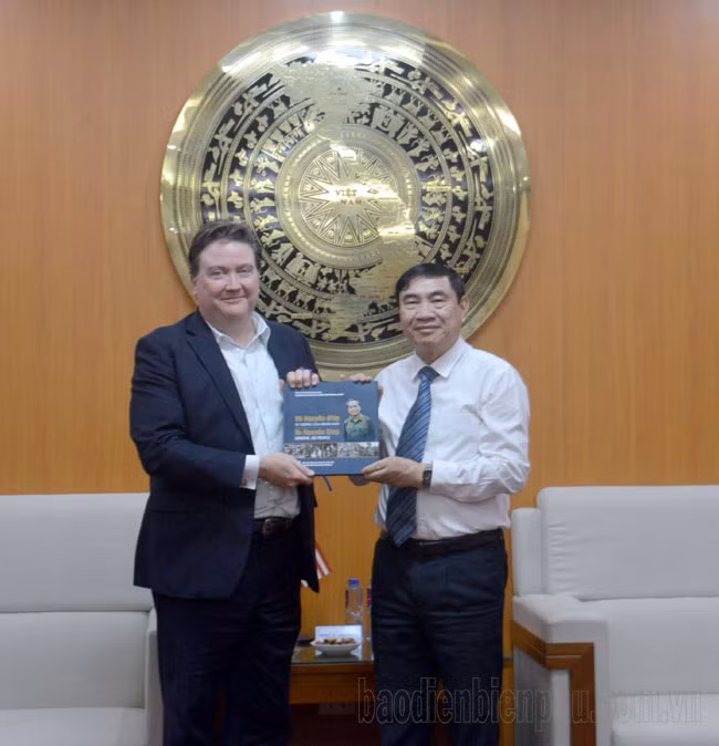 El secretario del PCV en Dien Bien, Tran Quoc Cuong, entrega un libro sobre el General Vo Nguyen Giap al embajador de Estados Unidos, Marc E. Knapper.