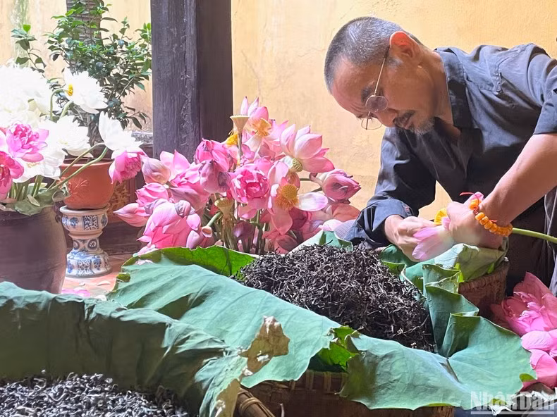 El artista de elaborar el té del loto Dam Quang Minh presenta la técnica de marinar el té de loto.