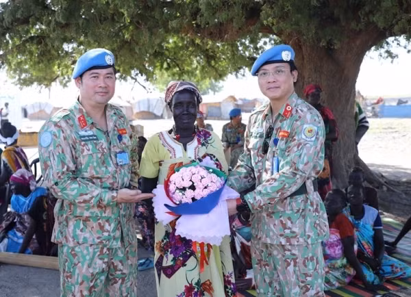 Representantes del hospital de campaña de segundo nivel número 4 de Vietnam regalan flores a una mujer sudsudanesa en ocasión del Día Internacional de la Mujer. 