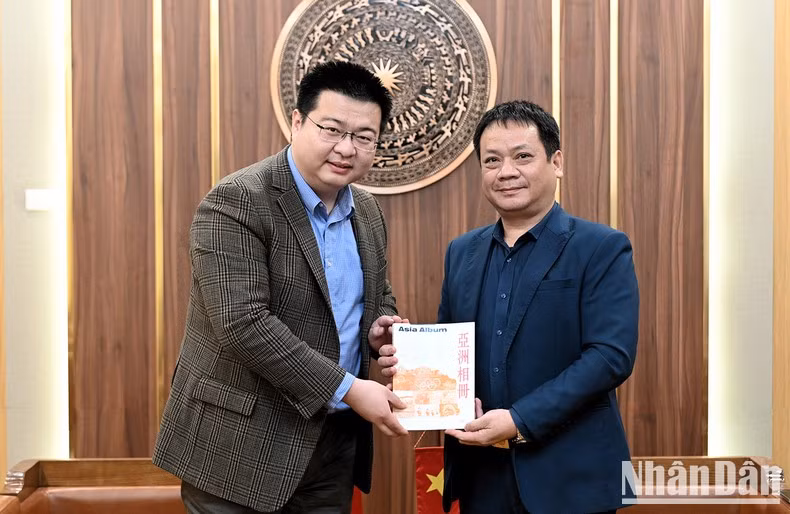 El jefe de la corresponsalía de la agencia de noticias Xinhua en Hanói, Zhouxue Mian, hace entrega de obsequios a Pham Song Ha, miembro del Consejo Editorial del periódico Nhan Dan y jefe del Departamento de Asuntos Político-Diplomáticos.