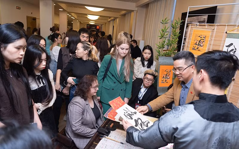 Estudiantes internacionales aprenden sobre caligrafía en el Festival de Vietnam en Rusia.