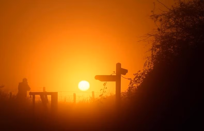 Visitantes al Parque Nacional South Downs (Inglaterra) toman fotos de la puesta de sol en la niebla el 1 de diciembre.