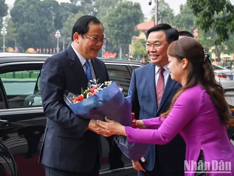 El personal de la Oficina del Parlamento vietnamita entrega flores para dar la bienvenida al primer ministro laosiano.