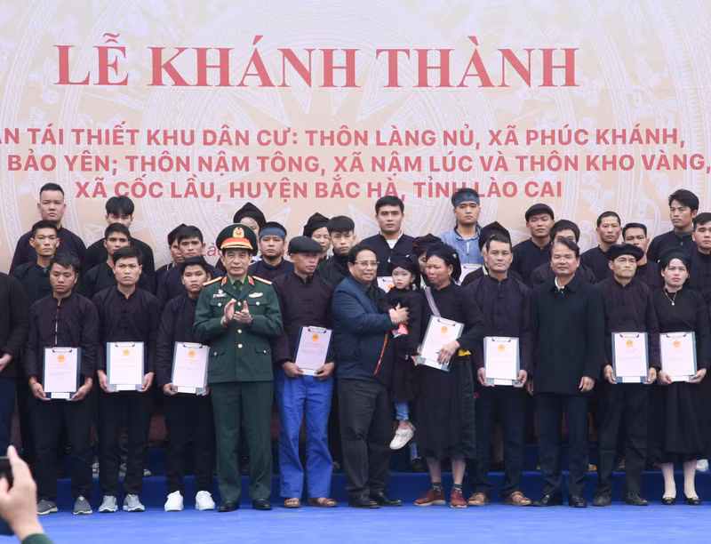 Minh Chinh y los dirigentes locales entregan certificados de derecho de uso de la tierra en nuevas viviendas a las familias de la aldea de Lang Nu.