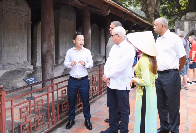 Los visitantes escuchan una explicación del significado del conjunto de 82 estelas de piedra en las que están tallados los nombres de los doctorados conservados en el Templo de la Literatura. (Foto: quochoi.vn)