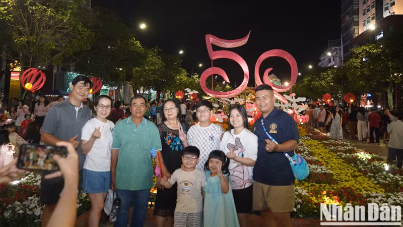 Muchas familias se toman fotos de recuerdo frente al cartel en saludo al Año Nuevo Lunar 2025 en la calle de flores Nguyen Hue.