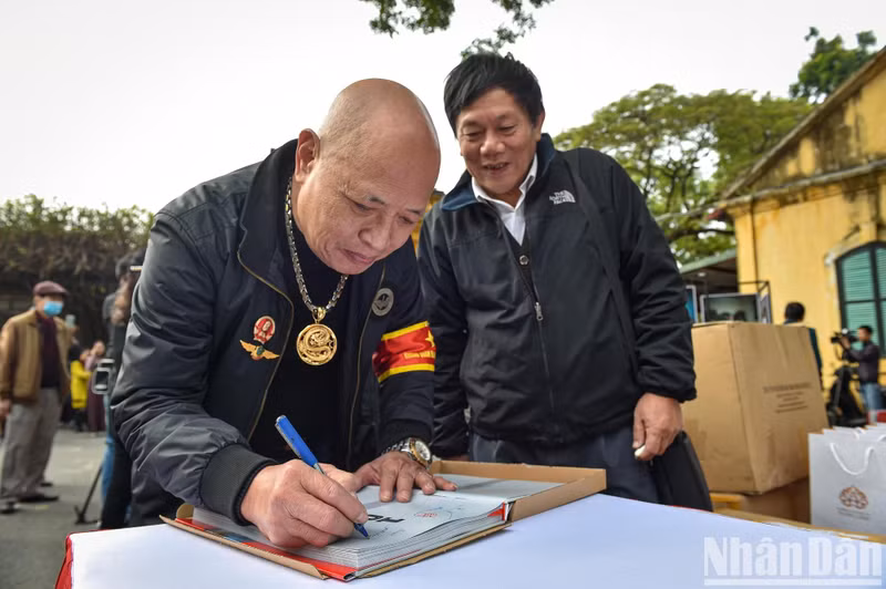 El expiloto del Ejército Popular de Vietnam, Nguyen Hong My, regala a los visitantes libros con su firma.