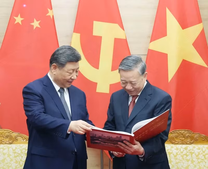 El secretario general del Partido Comunista de Vietnam, To Lam, entrega respetuosamente al secretario general del Partido Comunista y presidente de China, Xi Jinping, un libro de fotografías de la Agencia de Noticias de Vietnam, que incluye fotos típicas e impresionantes de las cinco visitas de Xi Jinping al país indochino. (Foto: VNA)
