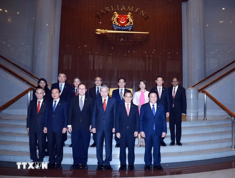 To Lam y Seah Kian Peng, junto con los delegados toman una foto grupal. (Foto: VNA)