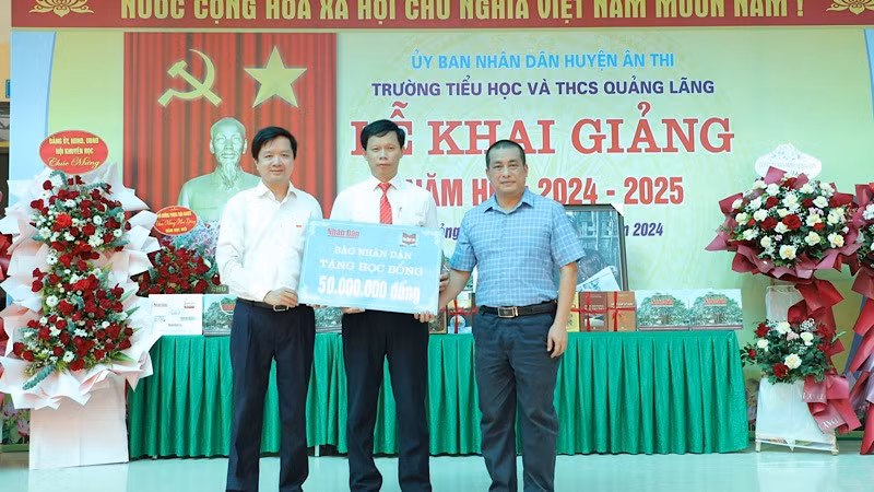 Representantes del periódico Nhan Dan entregan becas a la escuela.