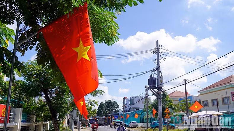 La calle de Le Van Luong se vuelve más animada cuando se cuelgan banderas rojas con estrellas amarillas a ambos lados de la calle.