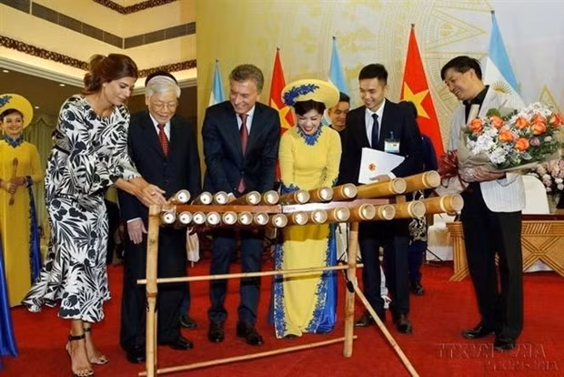El entonces presidente argentino, Mauricio Macri, intenta tocar un instrumento musical tradicional vietnamita durante su visita al país indochino en 2019. (Fotografía: VNA)