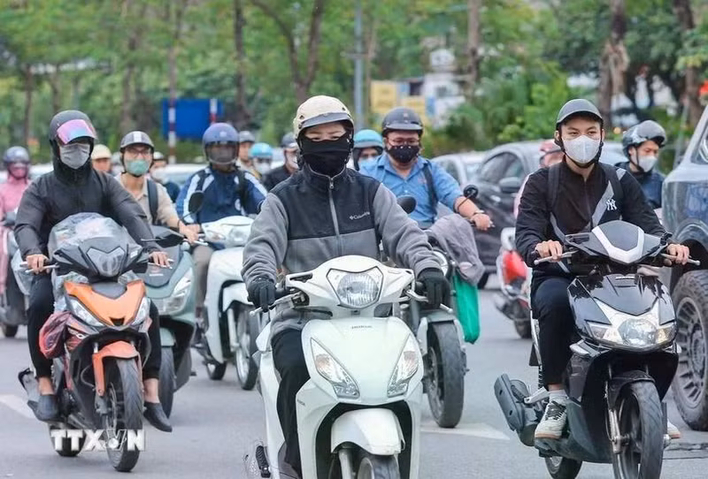 Motociclistas visten ropa abrigada y guantes al circular en la calle. (Fotografía: VNA)
