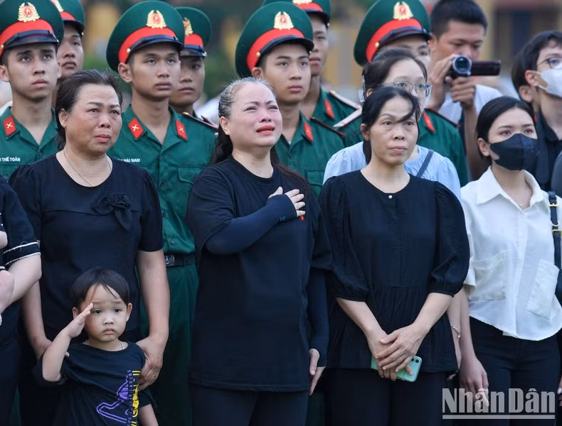 A la ciudadana se le saltan las lágrimas al ver ondear la bandera a media asta en señal de luto nacional por el fallecimiento del Secretario General del Partido, Nguyen Phu Trong.