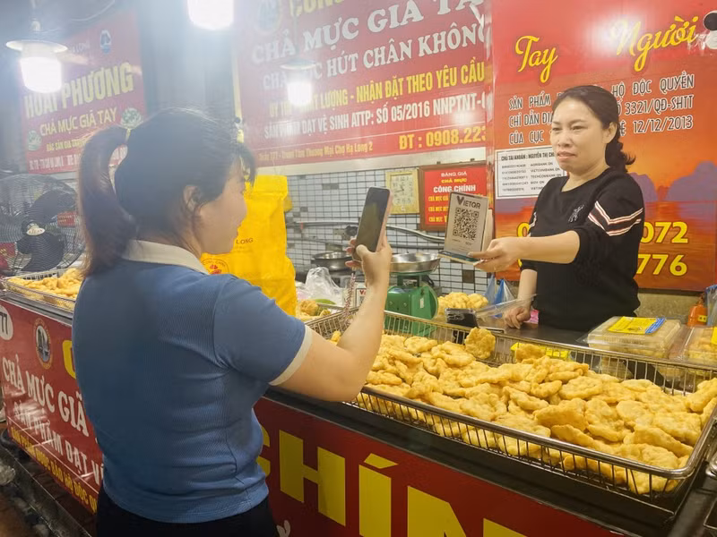 Una compradora realiza el pago sin efectivo en el mercado de Ha Long 2. (Fotografía: VNA)
