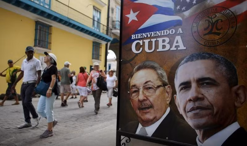 Unos turistas pasan junto un cartel con las efigies del presidente de Estados Unidos, Barack Obama, y de Cuba, Raúl Castro, colocado en la entrada a un restaurante en La Habana, el 17 de marzo de 2016. (Foto: Reuters)