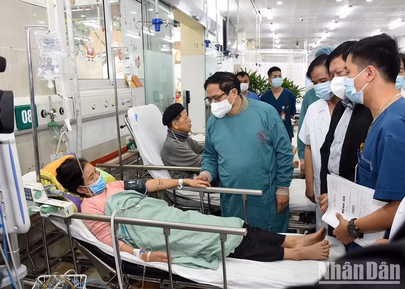 El premier visita a una paciente bajo tratamiento en el Centro de Emergencia A9, en el Hospital de Bach Mai.