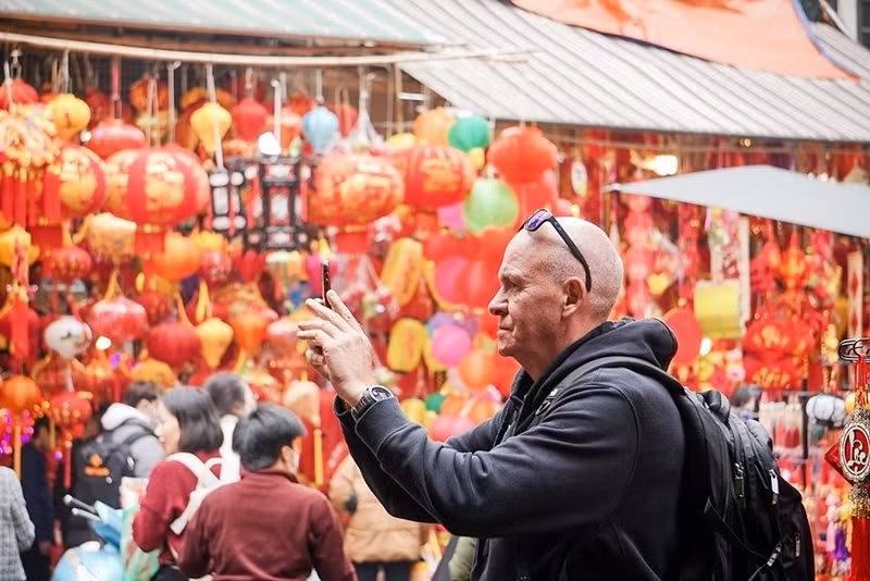 Un turista extranjero toma fotos sobre las preparaciones del Tet de los vietnamitas en el mercado de flores de Hang Luoc.