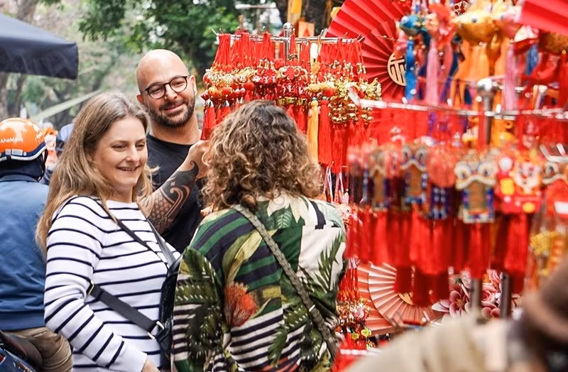 Los turistas extranjeros disfrutan del ambiente alegre en vísperas del Tet en el mercado de flores de Hang Luoc.