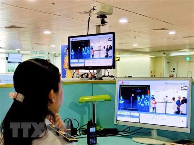 El personal del aeropuerto de Tan Son Nhat revisa la pantalla del termómetro remoto para los pasajeros internacionales que llegan a Vietnam. (Fotografía: VNA)