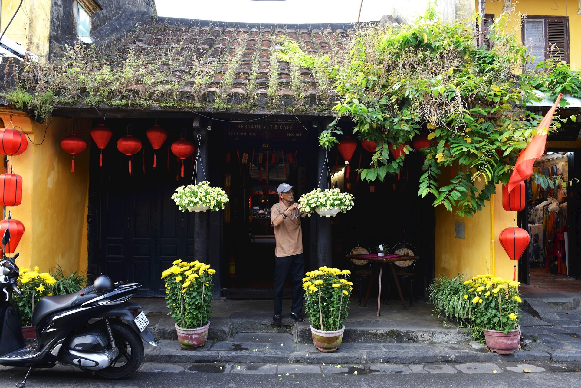 Un vecino aprovecha la mañana para podar las macetas frente a su casa y prepararse para recibir a los visitantes.